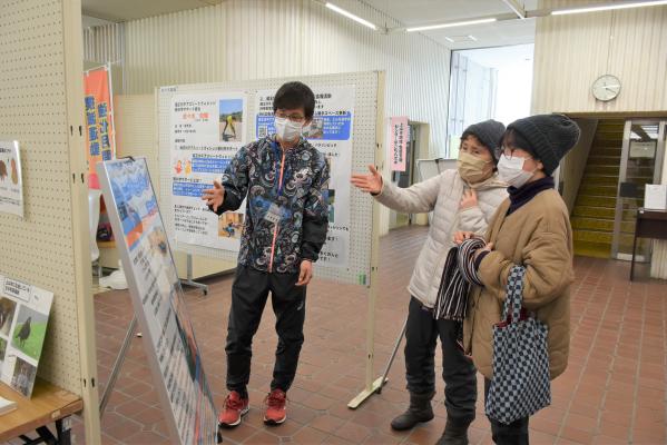 展示を見ながら協力隊員と話す市民