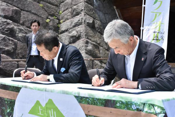 協定書にサインをする高橋社長(右)と横戸市長(左)